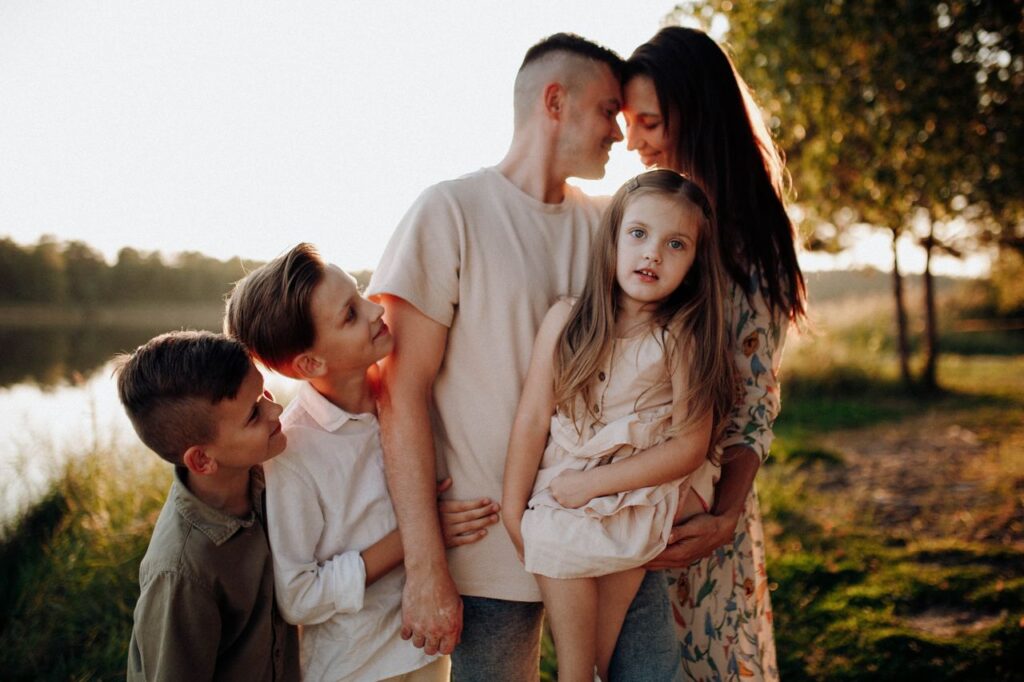 Family enjoying quality time together outdoors by the lake during sunset.