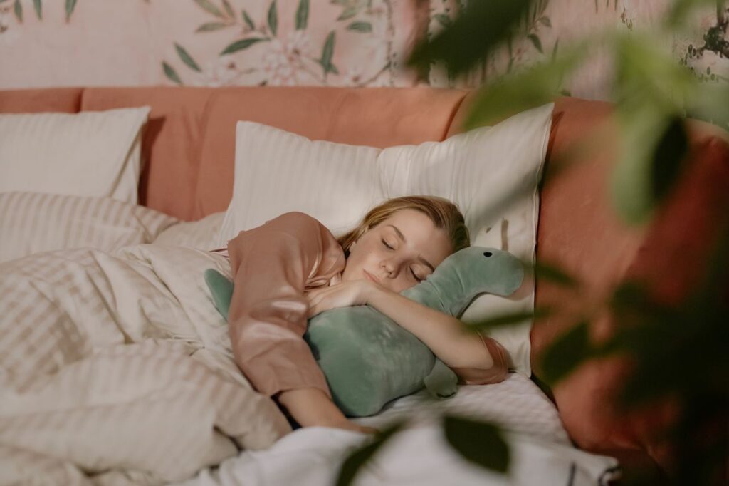 A woman peacefully naps in bed, hugging a plush dinosaur toy, surrounded by soft pillows.